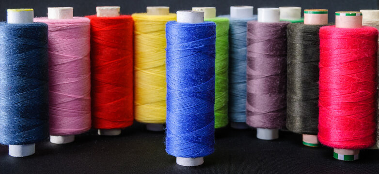 blue spool in focus against colorful spools of thread background