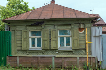 Fototapeta na wymiar The old wooden house and ge black cat sleeps on the window frame of the сountry house.