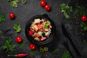 Delicious salad with chicken, olives and fresh herbs, a fresh salad on the menu of a fast food restaurant on a dark stone table. Healthy option of fast food..