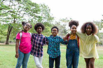 Cheerful African American children standing in row straight and hugging shoulder. diverse black children hugging shoulder in the park. Successful and teamwork concept