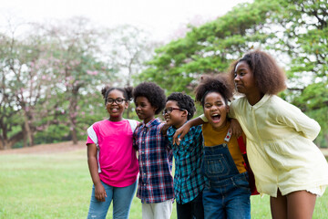 Cheerful African American children standing in row straight and hugging shoulder. diverse black children hugging shoulder in the park. Successful and teamwork concept
