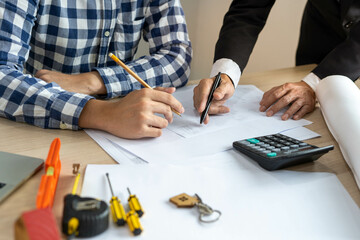 The head of the construction team and the owner of the house building company look at the blueprint...