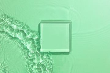 Empty white glass podium on transparent clear green calm water texture with splashes and waves in...