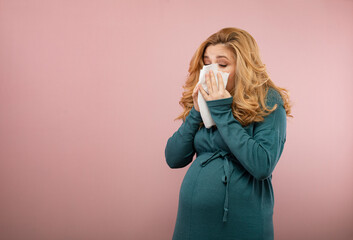 A pregnant woman blows her nose into a white handkerchief. Pregnant woman caught a cold