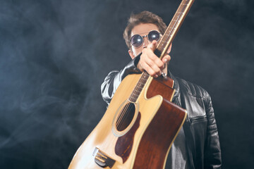 Obraz na płótnie Canvas man in black leather jacket holding guitar music celebrity lifestyle