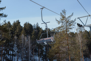 Empty chair lift at ski resort on background of trees in winter