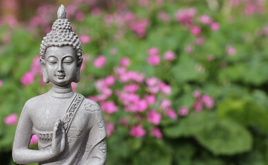 Buddha Statue in Garden with blurred pink flower background