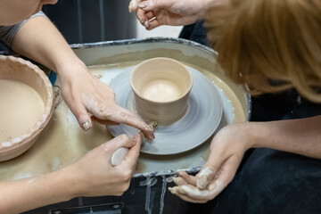 the master demonstrates to the student the process of making and processing a clay billet on a potter's wheel