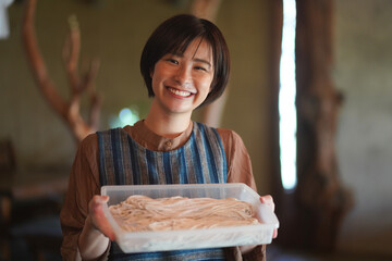 手打ちしたそばを持つ女性