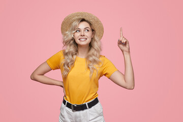 Cheerful woman in summer outfit pointing up