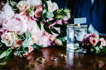 Stylish men's rings, suit, flowers and perfume for groom. Wedding accessories on rustic brown...