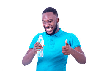 young man holding a bottle of mineral water and showing his thumb while smiling.