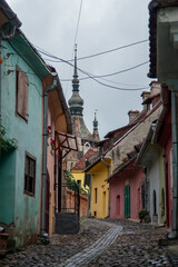 Wąska kamienna uliczka z kolorowymi budynkami i kościołem - obrazy, fototapety, plakaty
