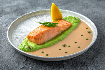 Salmon fillet on spinach avocado puree with shrimp sauce. Ready menu for the restaurant. Neutral gray blue textured background
