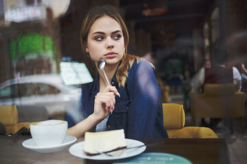 pretty woman sitting at a table in a cafe pensive look
