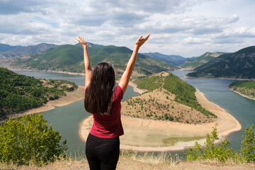 Fototapeta na wymiar Woman arms outstretched by the mountain river. Successful, business and sport concept