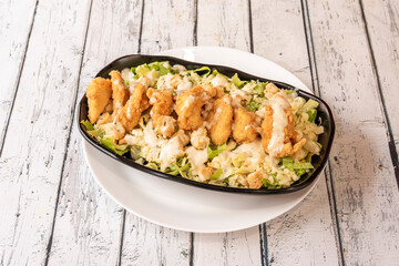 Caesar salad with crispy chicken coated in flour and breadcrumbs, croutons, iceberg lettuce and mayonnaise sauce