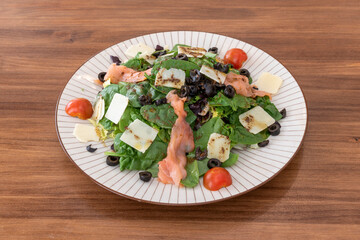 Great spinach salad with smoked salmon, Parmesan cheese slices, sliced black olives and olive oil