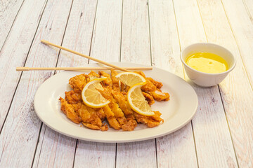 Chinese recipe for chicken breast fillets breaded, fried and chopped with lemon slices and Chinese lemon sauce with chopsticks