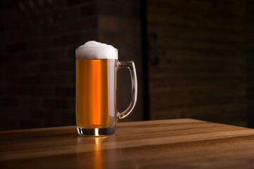 Glass of light beer on a dark pub.