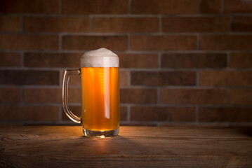 Glass of light beer on a dark pub.