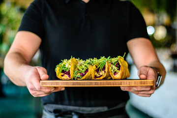 Waiter holding a dish of tacos