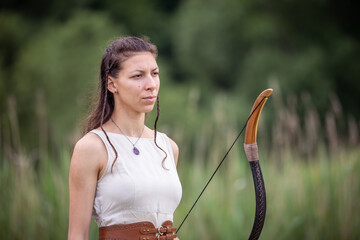 A Hungarian woman in a linen dress with a bow is standing on the field