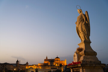 The skyline of Cordoba, Andalusia, Spain. A religious statue in the foreground. The city skyline in the background, with the famous Mezquita (meaning: mosque).