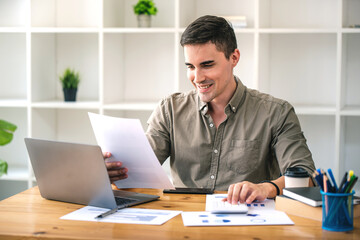 Fototapeta premium confident young businessman Work from home with laptop and documents on the desk.