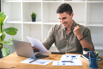 confident young businessman Work from home with laptop and documents on the desk.
