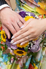 Fototapeta premium Put your left hand with a ring on a bouquet of summery yellow and purple flowers