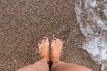 Woman feet .Standing on beach barefoot. Covered with sand and water