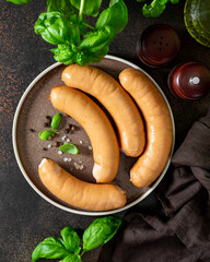 Pork sausages in a plate on a dark culinary background top view