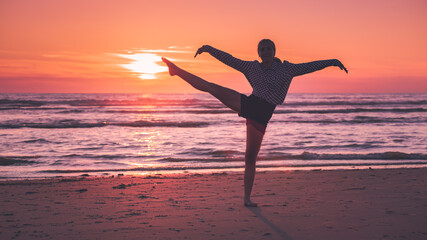 Jeune fille faisant du sport sur la plage, au coucher du soleil.