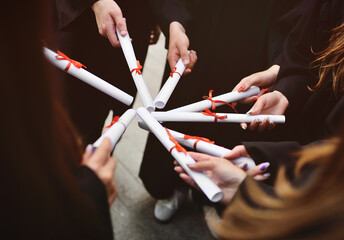 graduate students in black robes holding diplomas or certificates of graduation from a higher...