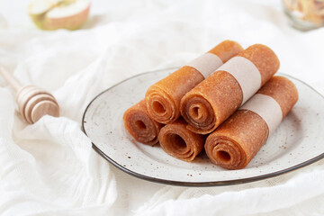 Apple pastille rolls, marshmallow with honey on ceramic kitchen board and white tablecloth.
