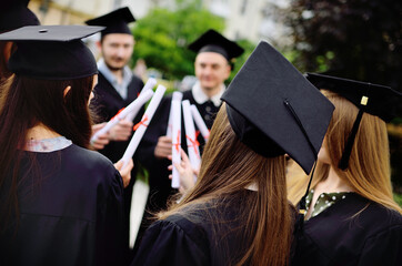group of university graduates in student robes or mantle and square hats at the graduation ceremony...