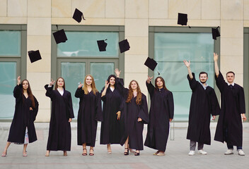students in robes throw up academic caps and are happy to receive higher education.