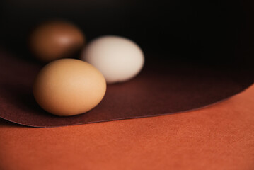Chicken eggs are laid in a row on brown paper. Paper rolled into a spiral or oval. Easter eggs for the holiday.