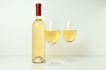 Bottle and glasses of wine on white table