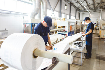 Workers in a factory carry out technological processes on a conveyor line in protective overalls
