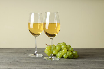 Glasses of white wine and grape on gray textured table