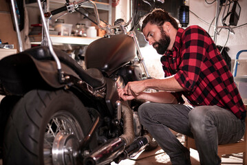 Obraz na płótnie Canvas Junger Mechaniker repariert Motorrad, Biker, Werkstatt, Lange Haare, Bartträger