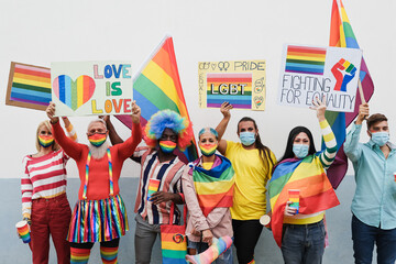 Gay people having fun at pride parade with LGBT flags and banners outdoors - Main focus on senior...