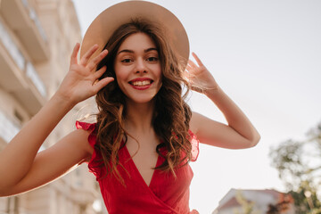 Close shot photography of cheerful girl touching her hat and beautiful long hair. Woman happy to be outside after the lockdown and enjoy the summer and warm weather in her favourite dress 
