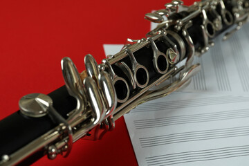 Clarinet and music sheets on red background