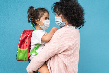 Mother hugging her daughter going back to school during coronavirus outbreak - Focus on woman face