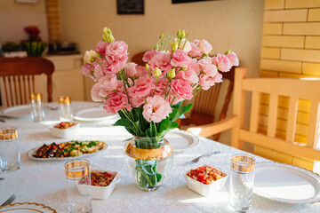bouquet of pink flowers in a vase on the table served on the terrace. 