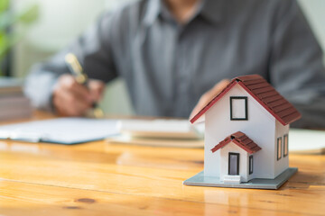 Property investment concept, image of small house model on the table.and home loan insurance.