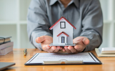 Property investment concept, image of small house model on the table.and home loan insurance.
